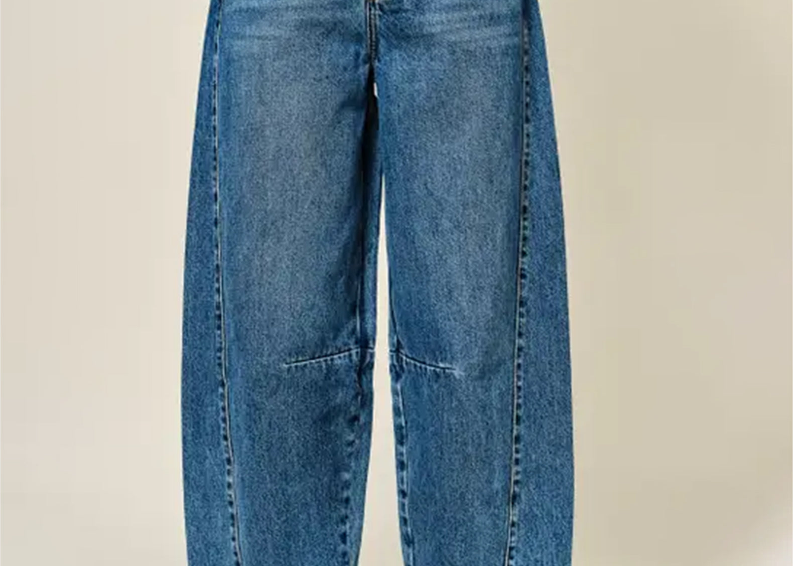 A person wearing wide-leg cropped blue denim jeans with brown leather loafers, shown from the waist down against a plain light beige studio background.