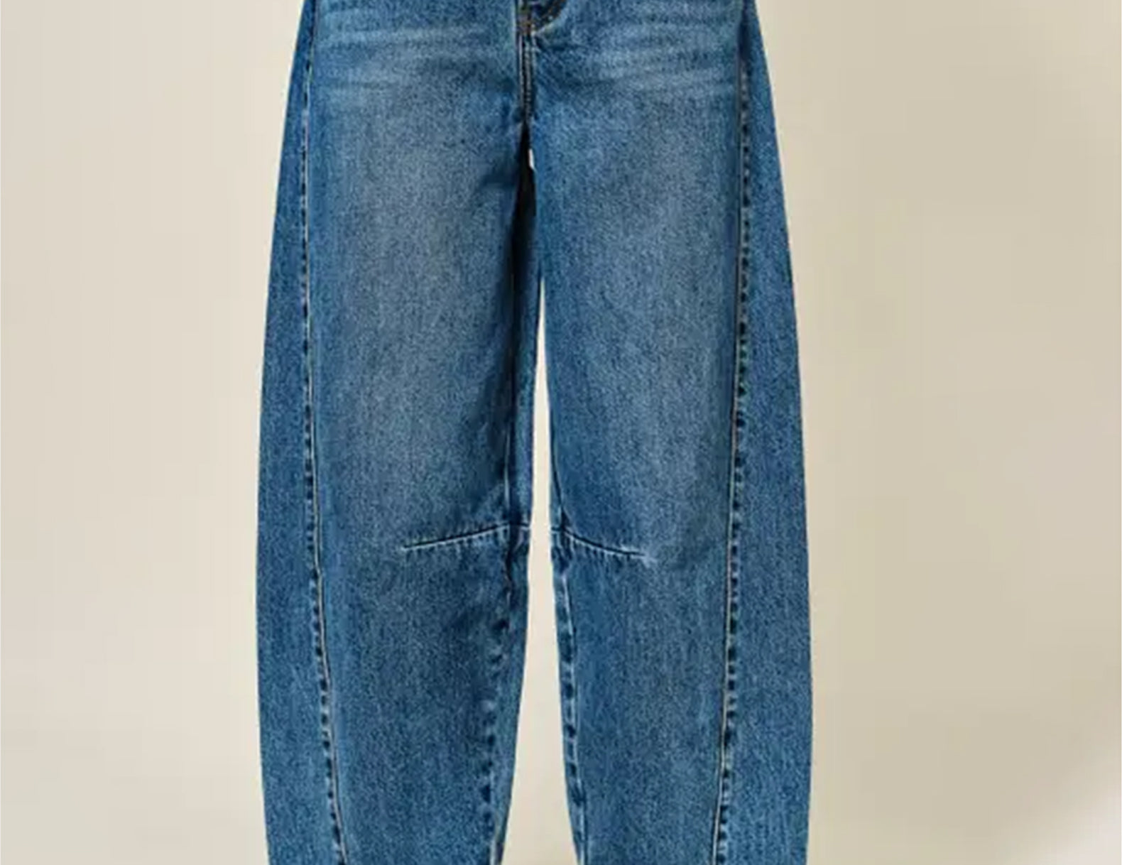 A person wearing wide-leg cropped blue denim jeans with brown leather loafers, shown from the waist down against a plain light beige studio background.