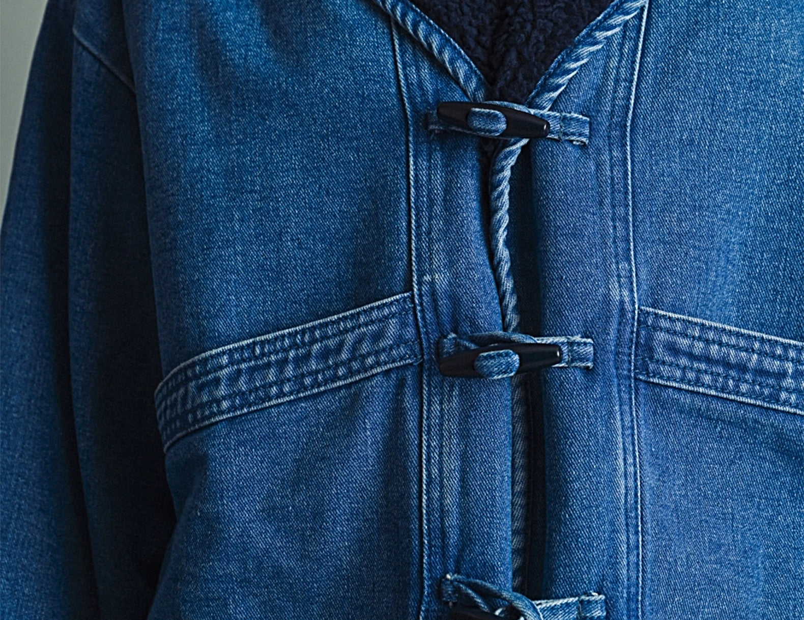 Close-up of the toggle closures, twisted rope trim and navy sherpa collar on the Faye denim jacket
