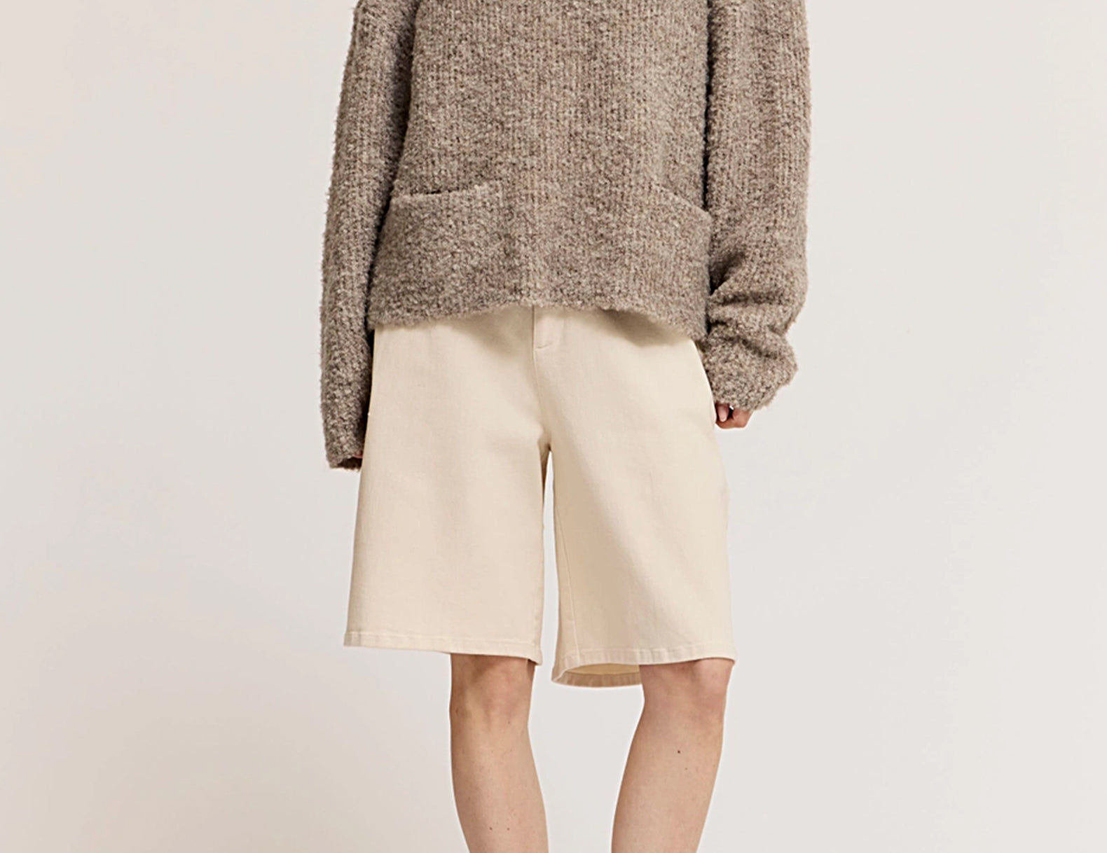 Woman wearing oversized bouclé sweater with Bermuda shorts and ballet flats