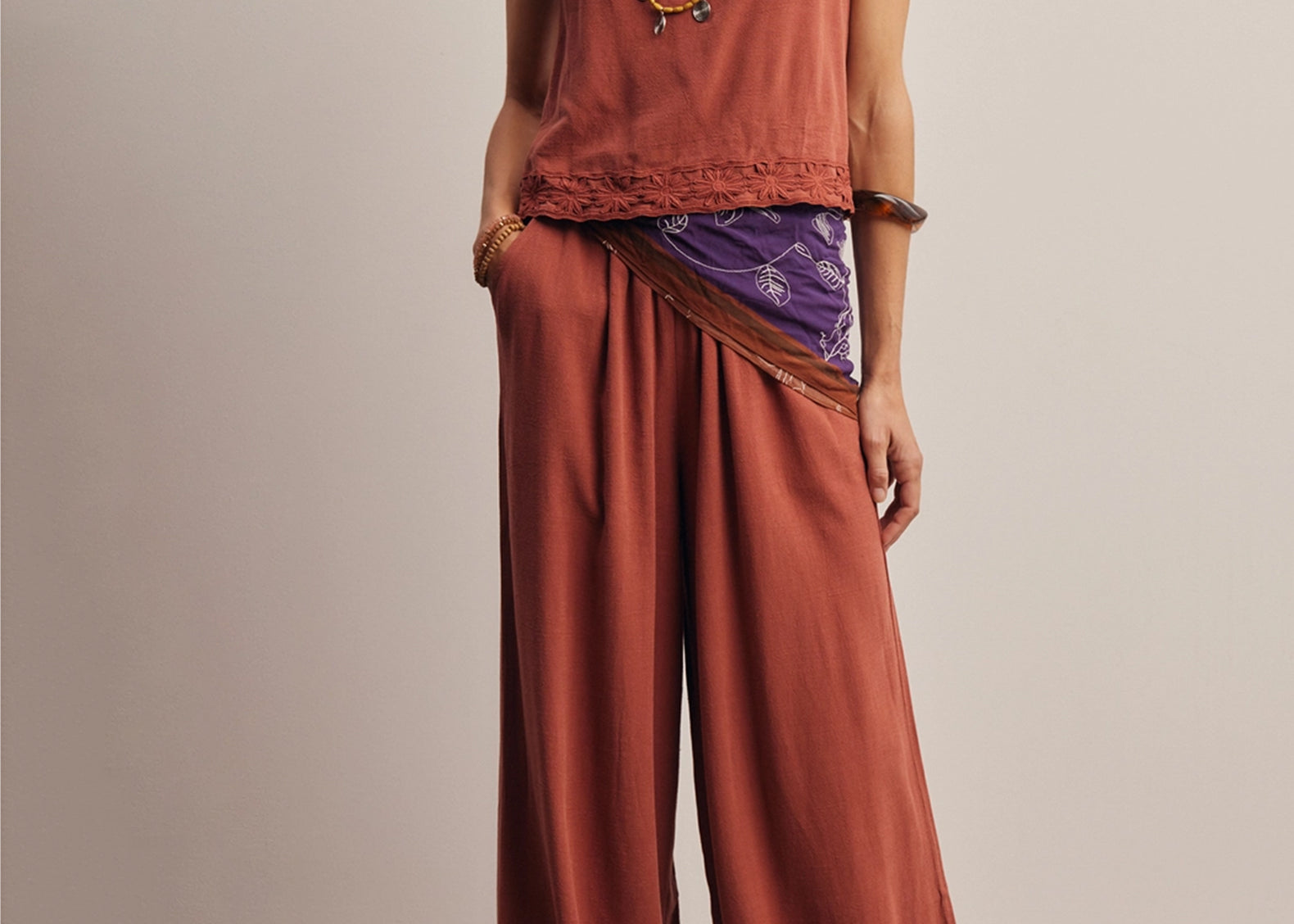 Front view of the Layla Embroidered Masala Pant, high-waisted wide-leg pants in red-brown linen-blend with daisy embroidered hems