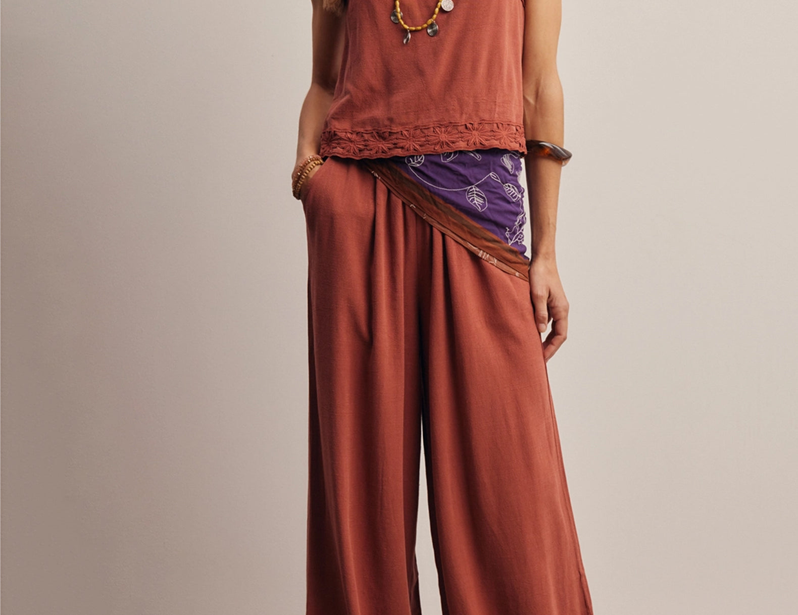 Front view of the Layla Embroidered Masala Pant, high-waisted wide-leg pants in red-brown linen-blend with daisy embroidered hems