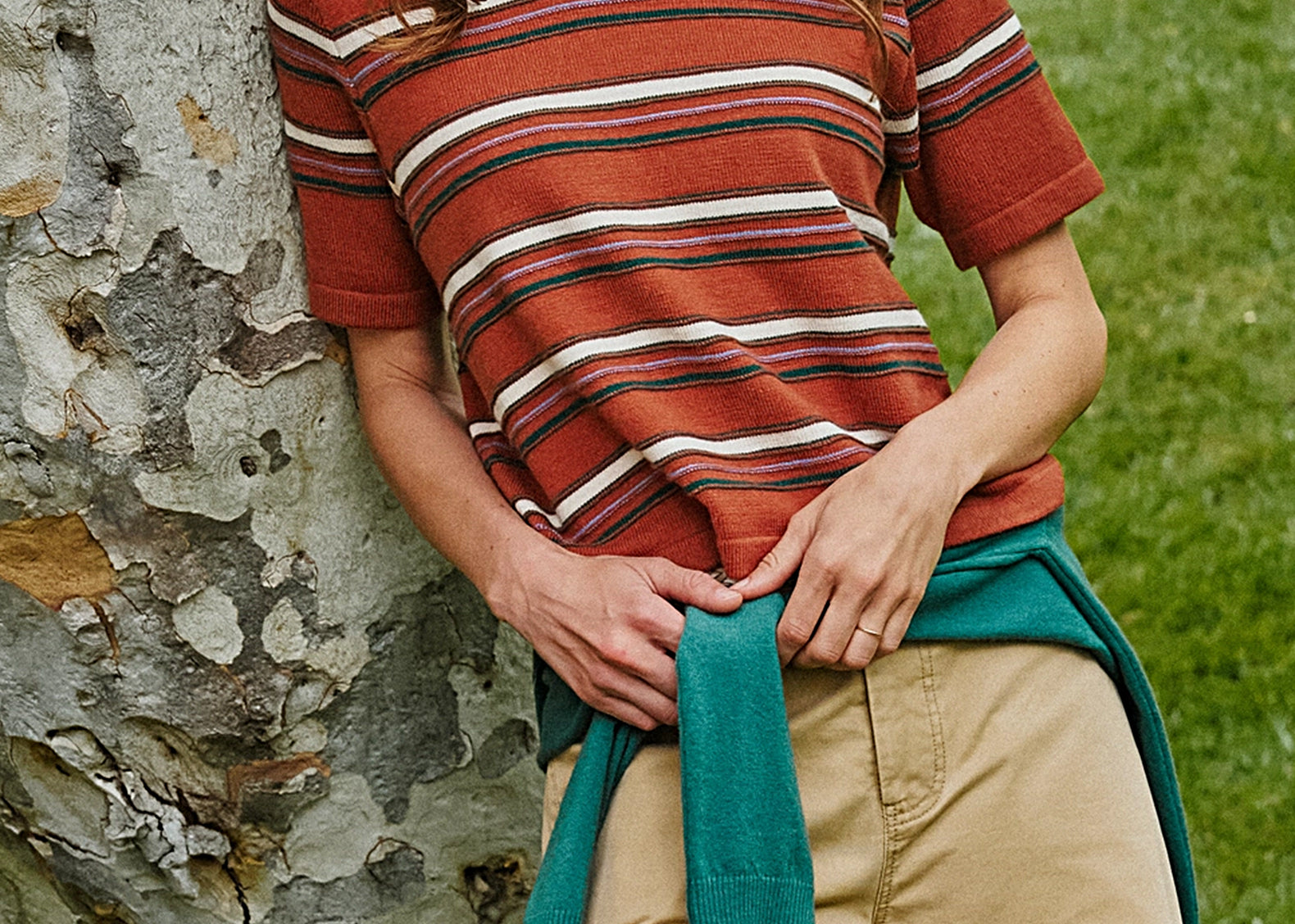 Woman wearing rust striped sweater-knit tee with green crew neck, front view outdoors