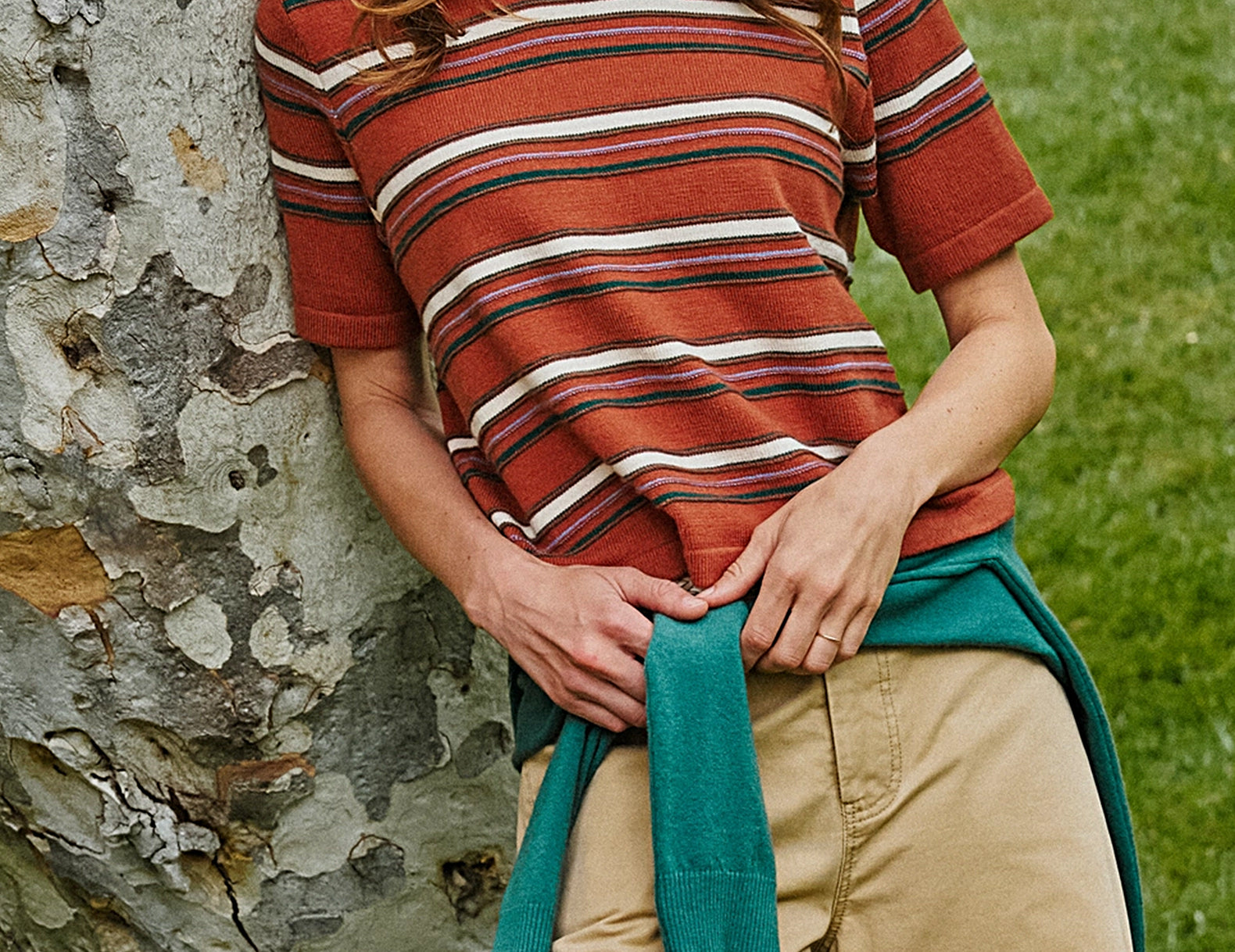Woman wearing rust striped sweater-knit tee with green crew neck, front view outdoors