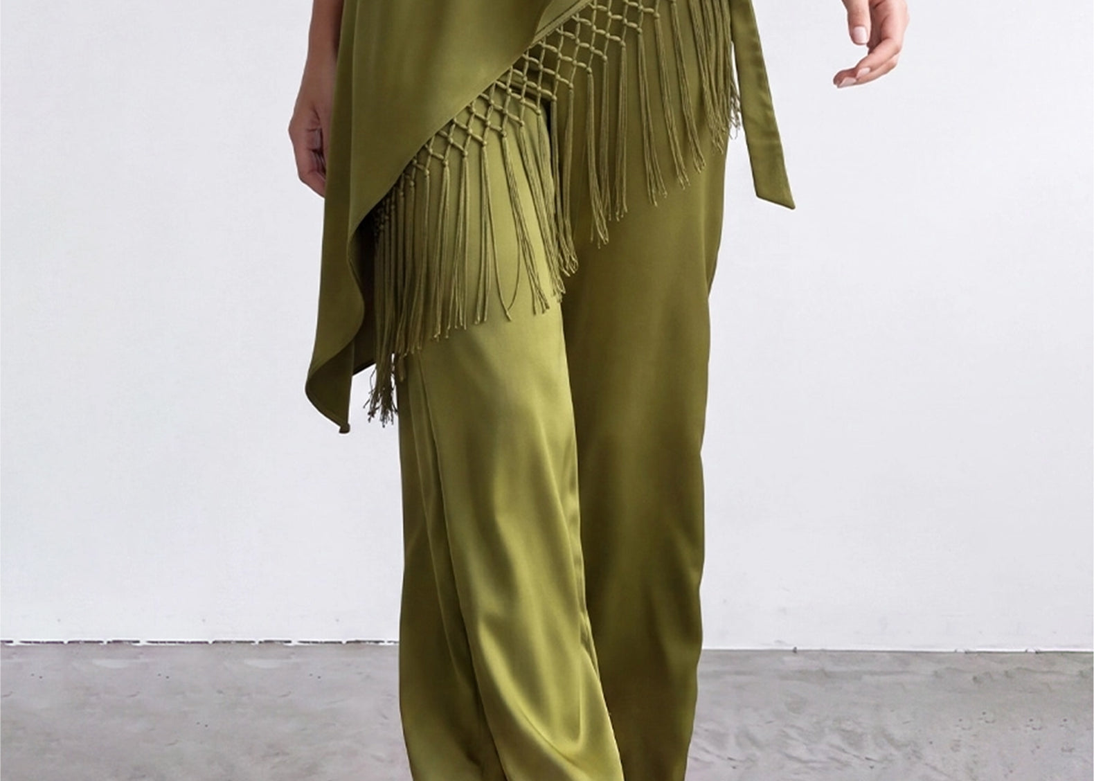 Olive satin pants and knotted fringe scarf in motion, front view