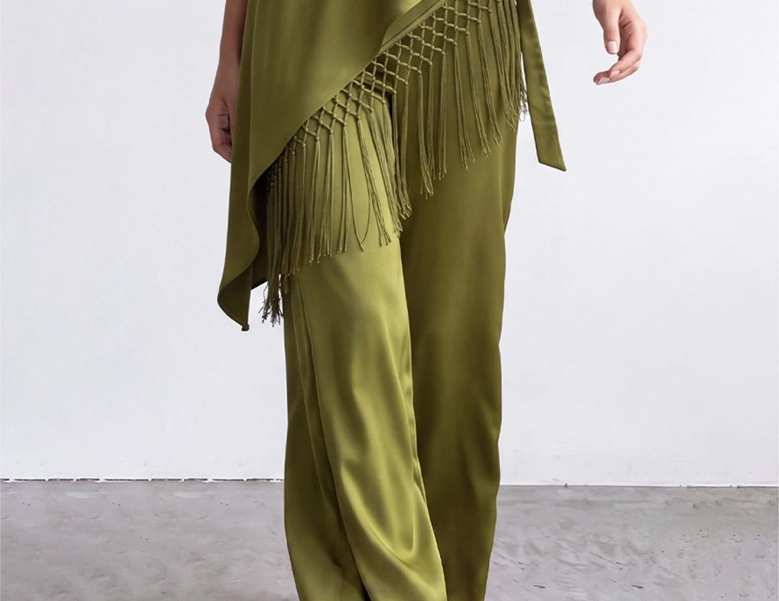 Olive satin pants and knotted fringe scarf in motion, front view