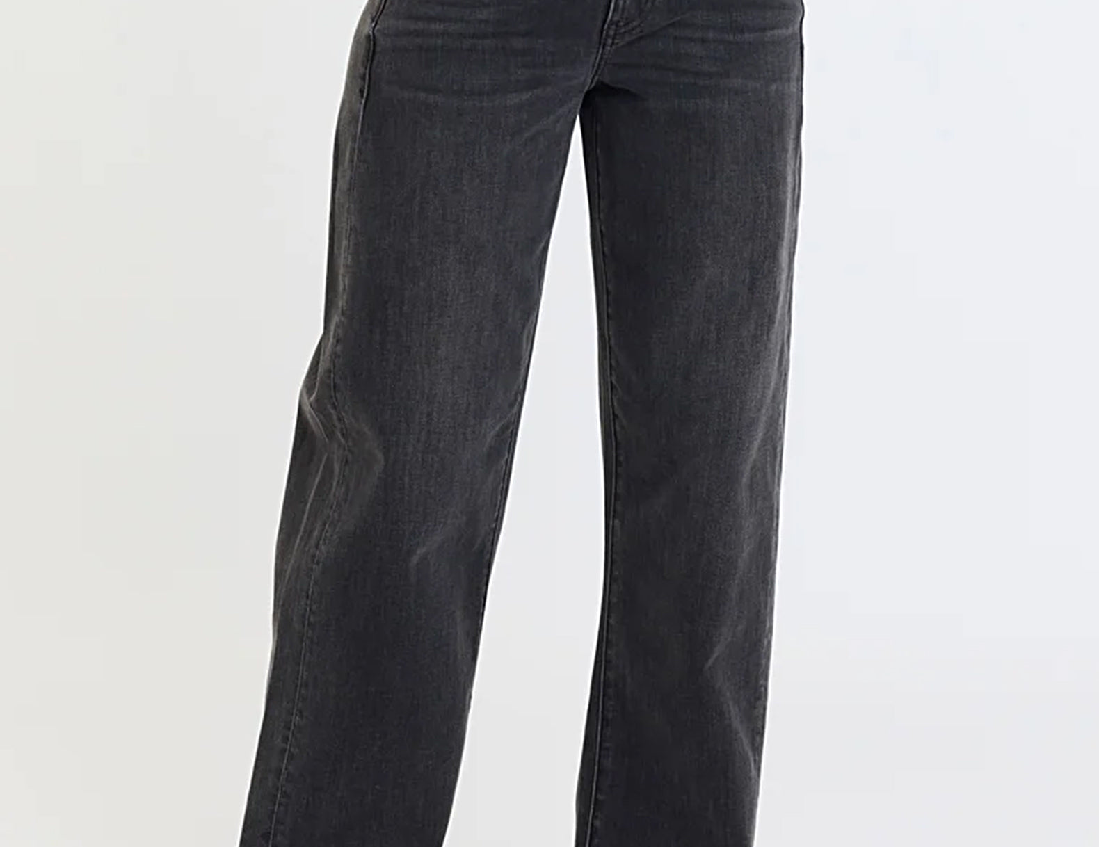 A person wearing dark charcoal gray wide-leg jeans, styled with a white cropped top and dark brown leather shoes, standing against a plain white studio background.