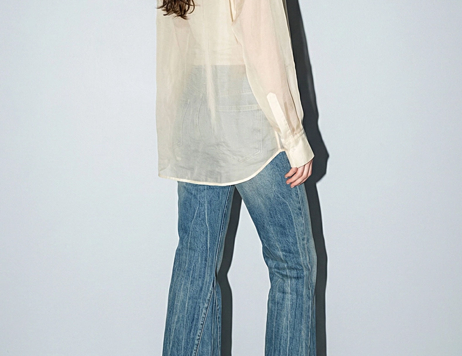 Back three-quarter view of the cream organza shirt with curved hem