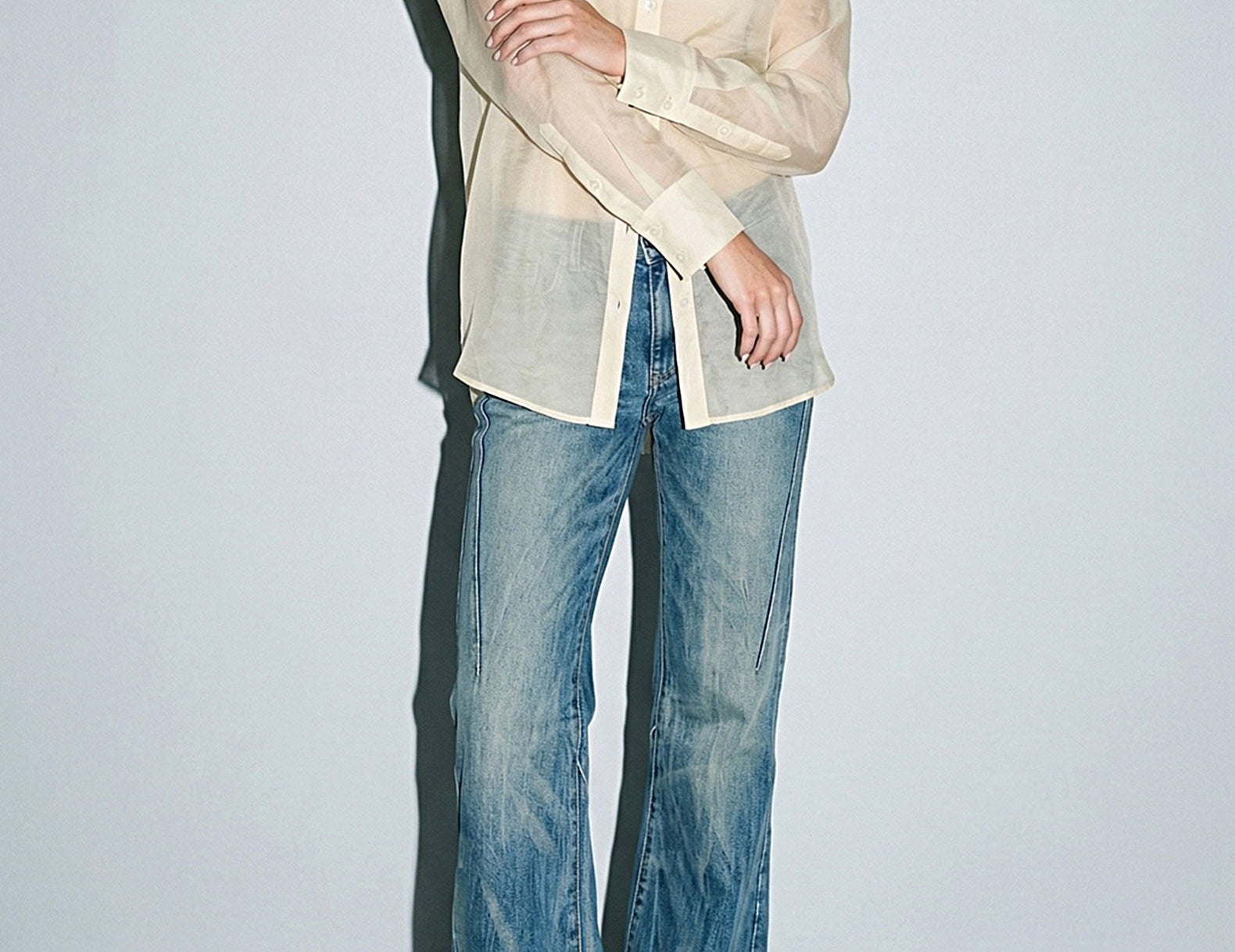 Front view of the sheer button-down blouse with arms crossed, showing button cuffs
