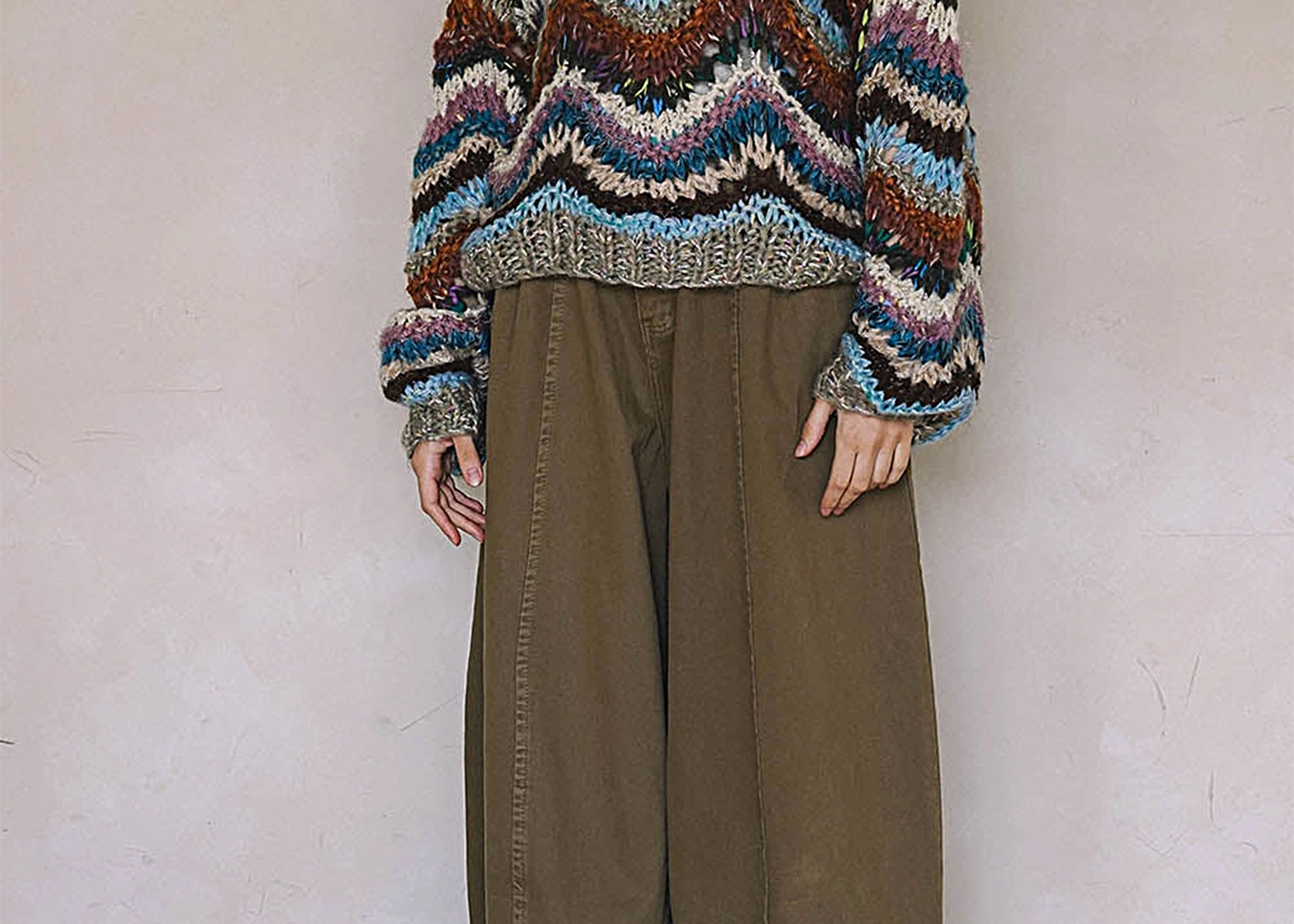 Woman wearing multicolor wavy striped hand knit sweater, full-length front view
