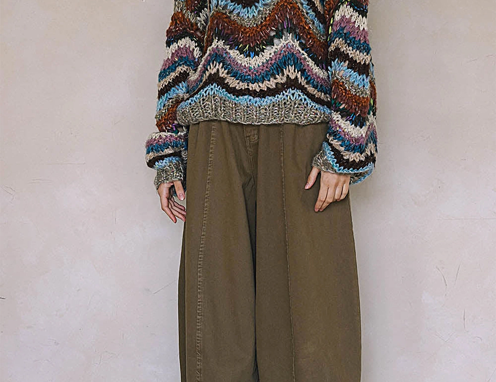 Woman wearing multicolor wavy striped hand knit sweater, full-length front view