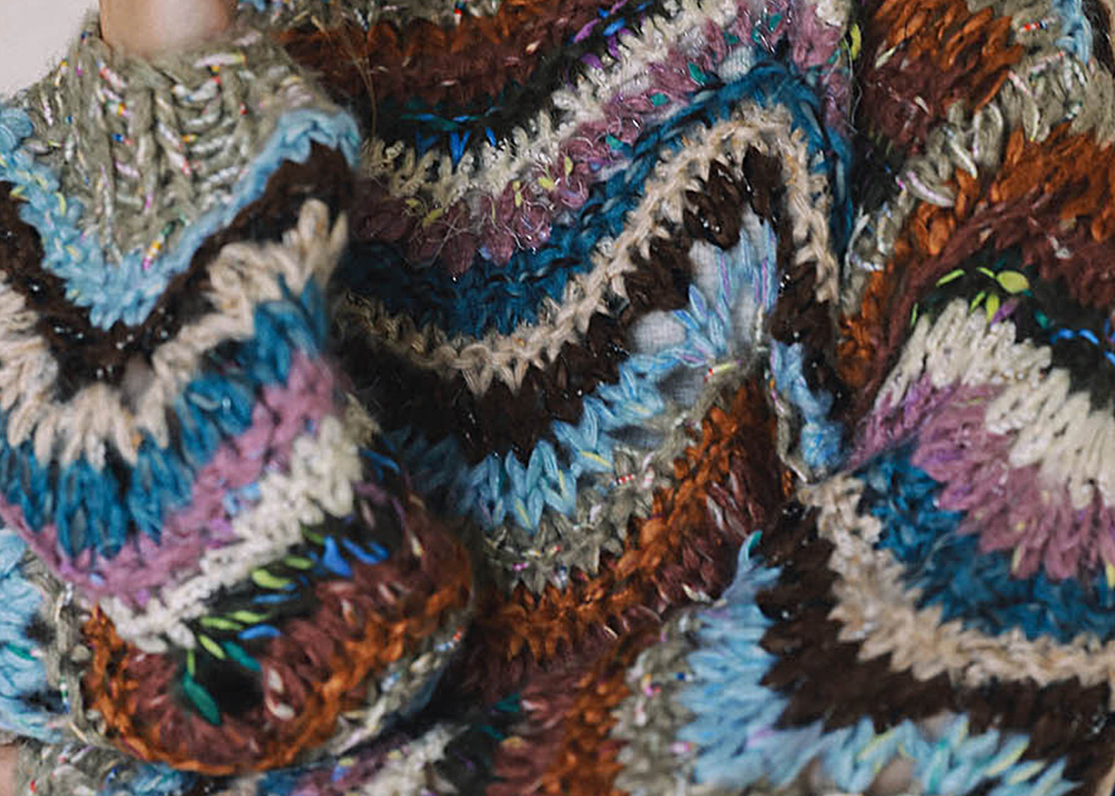 Close-up of chunky hand knit sweater with blue, lavender and rust zigzag stripes
