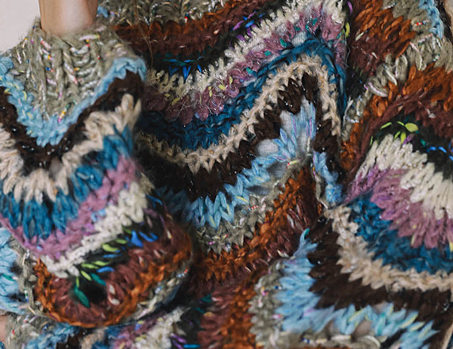 Close-up of chunky hand knit sweater with blue, lavender and rust zigzag stripes
